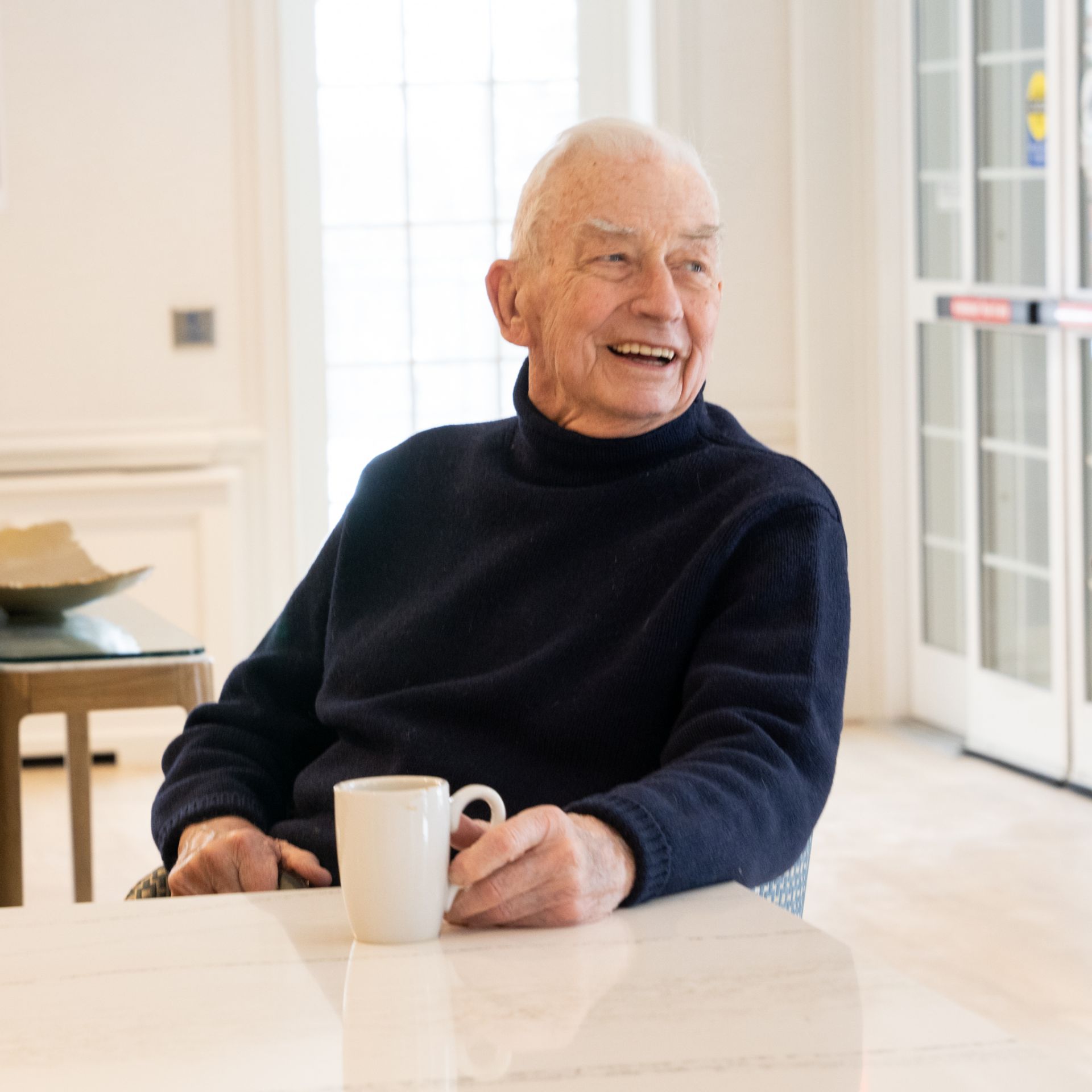 An Osborn resident joyfully enjoys a coffee in a communal sitting room