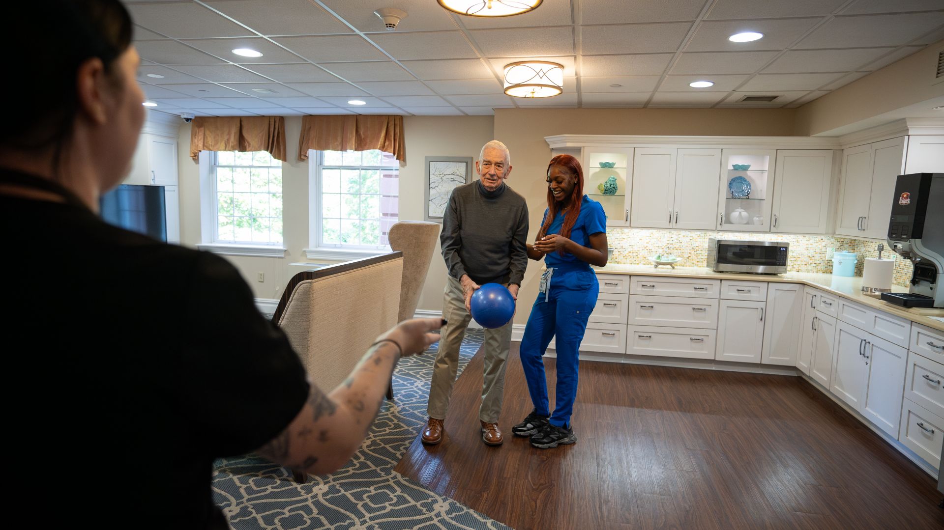 Two skilled nurses guide a resident in a rehabilitation activity