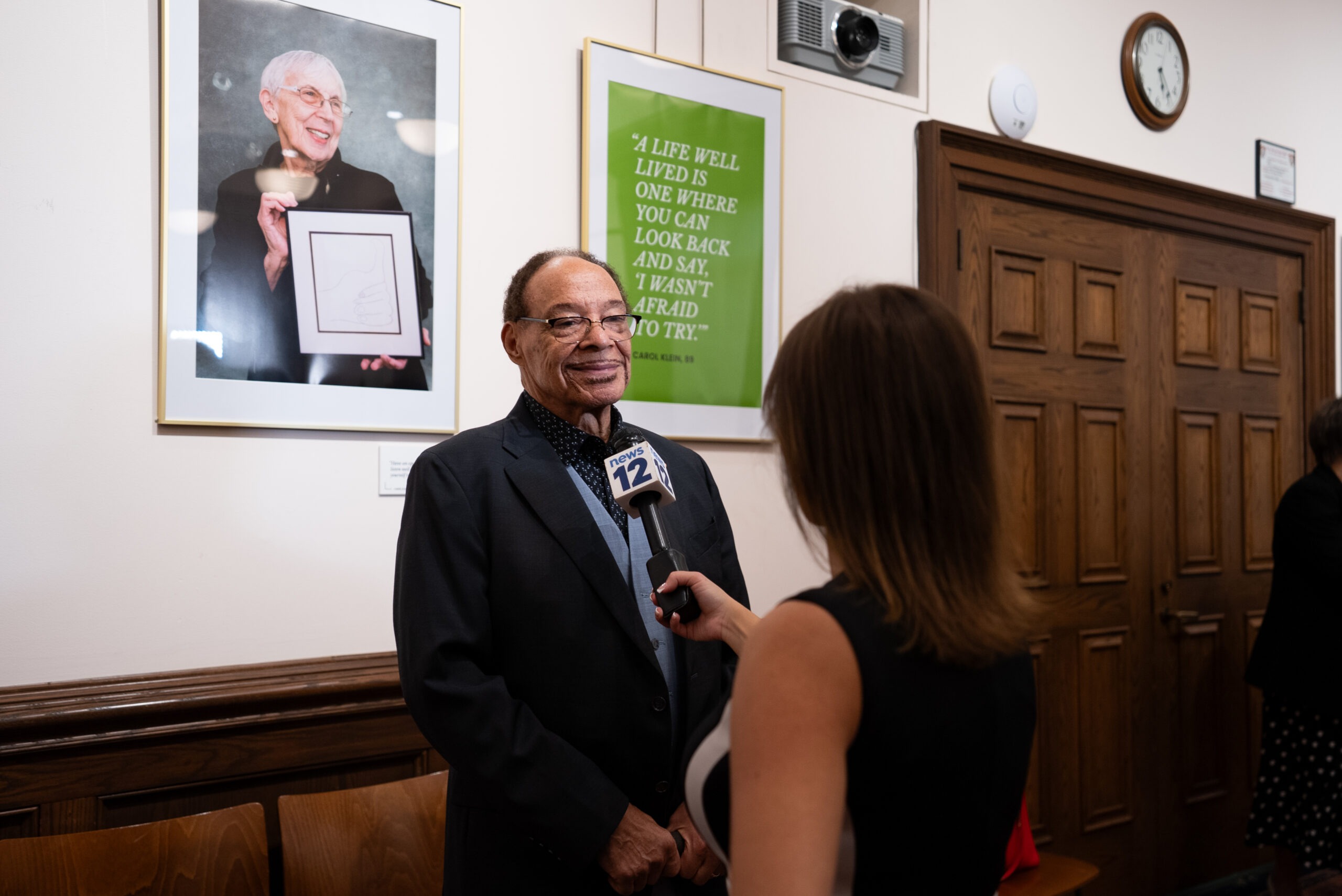 An Osborn resident and Wisdom Gallery honoree speaks to the press at the Rye Reading Room exhibit