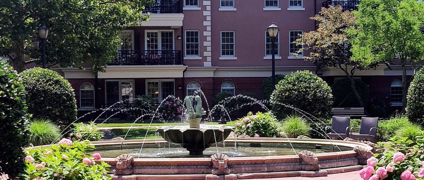 Exterior view of The Osborn senior living community in Rye, NY, featuring the historic building, fountain, and gardens