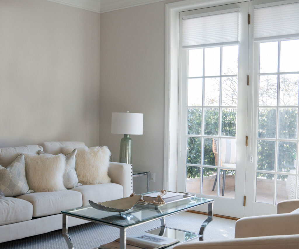 Bright living room in a resident's apartment at The Osborn in Rye, NY, with a cozy sofa and French doors leading outside